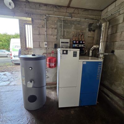 Chaudière Easypell avec réservoir de stockage et vase d'expansion dans une salle de chauffe en béton