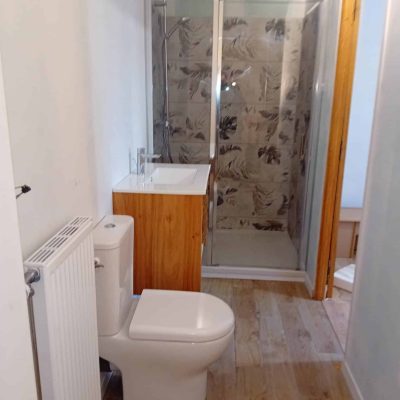 Salle de bains moderne avec WC, lavabo bois et douche carrelée à motifs